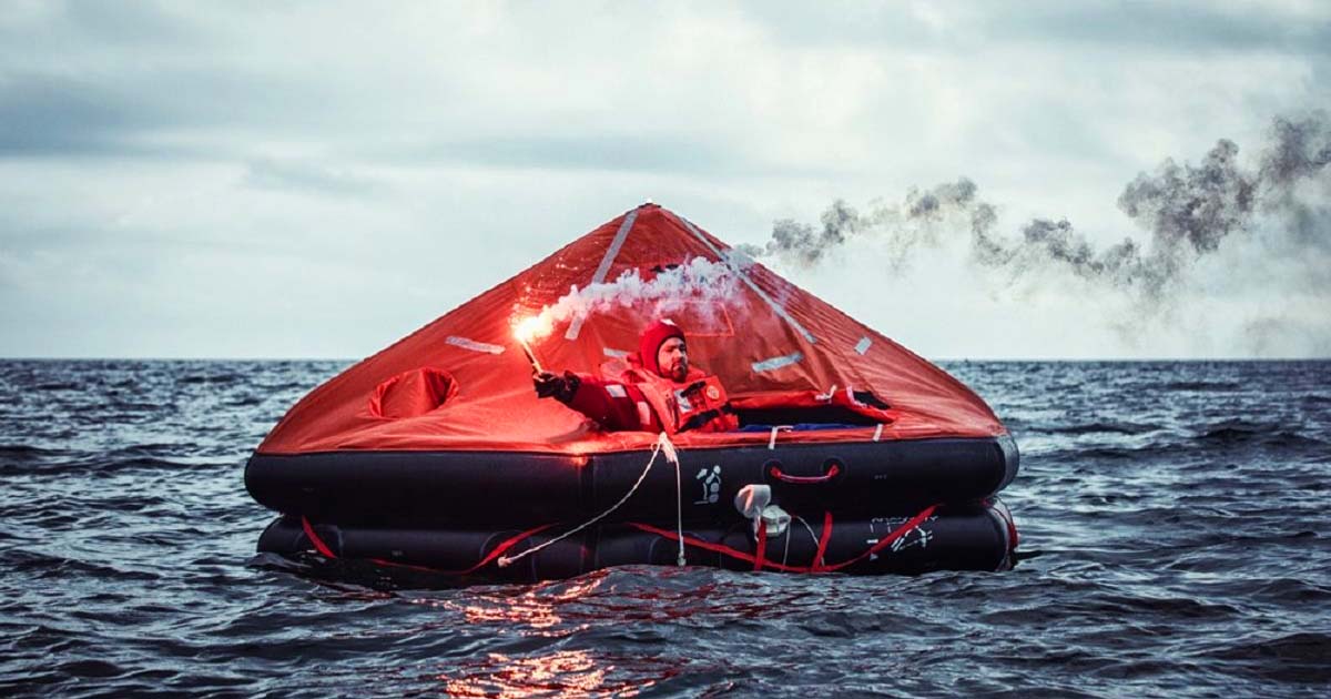 A person riding a liferaft and holding a hand flare as his distress signal.